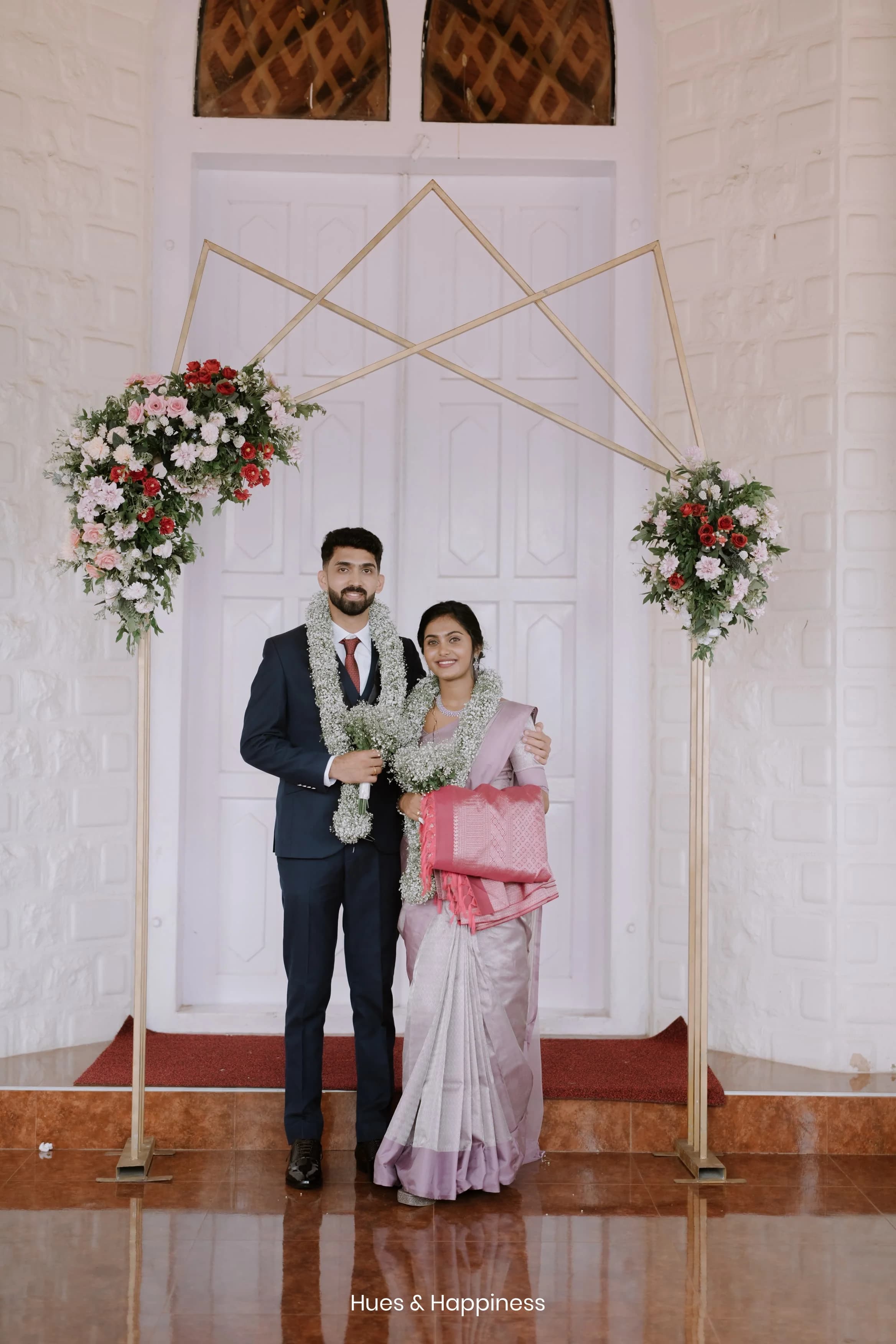 Newly married couple standing beneath a floral arch